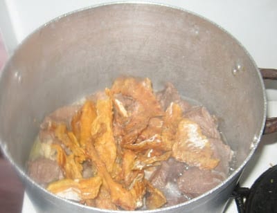 adding washed stock fish pieces to boiling beef